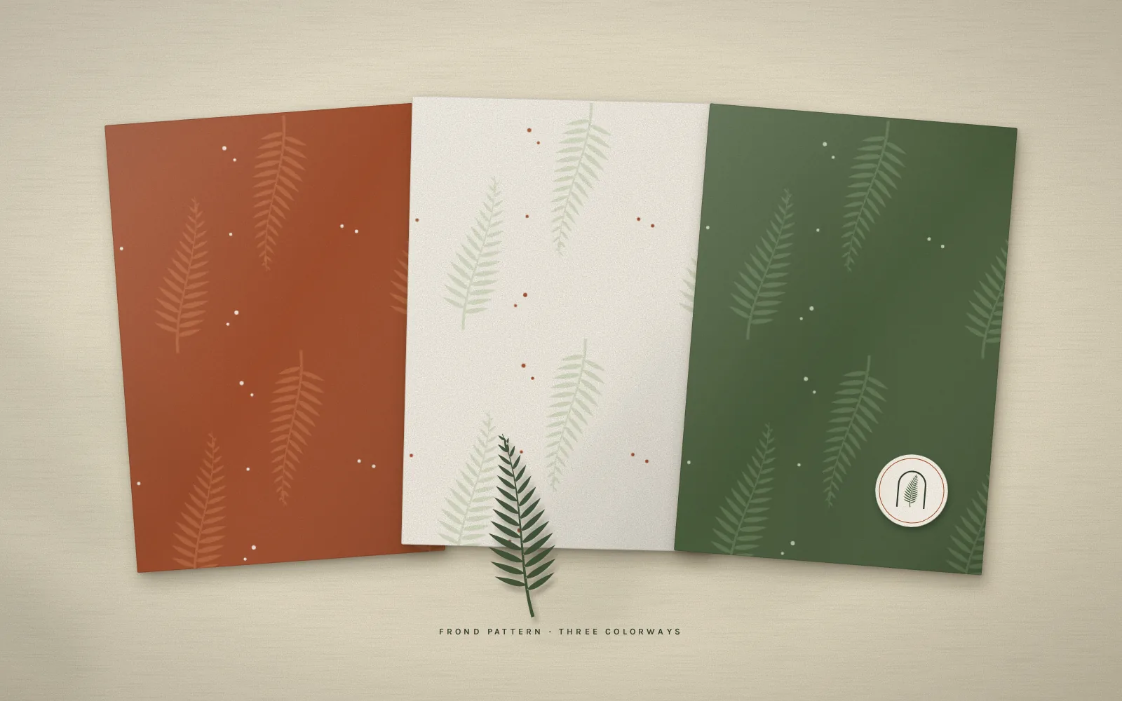 The Larkmoss frond pattern in three colorways: clay, oat and moss, with a pressed fern and an emblem seal.